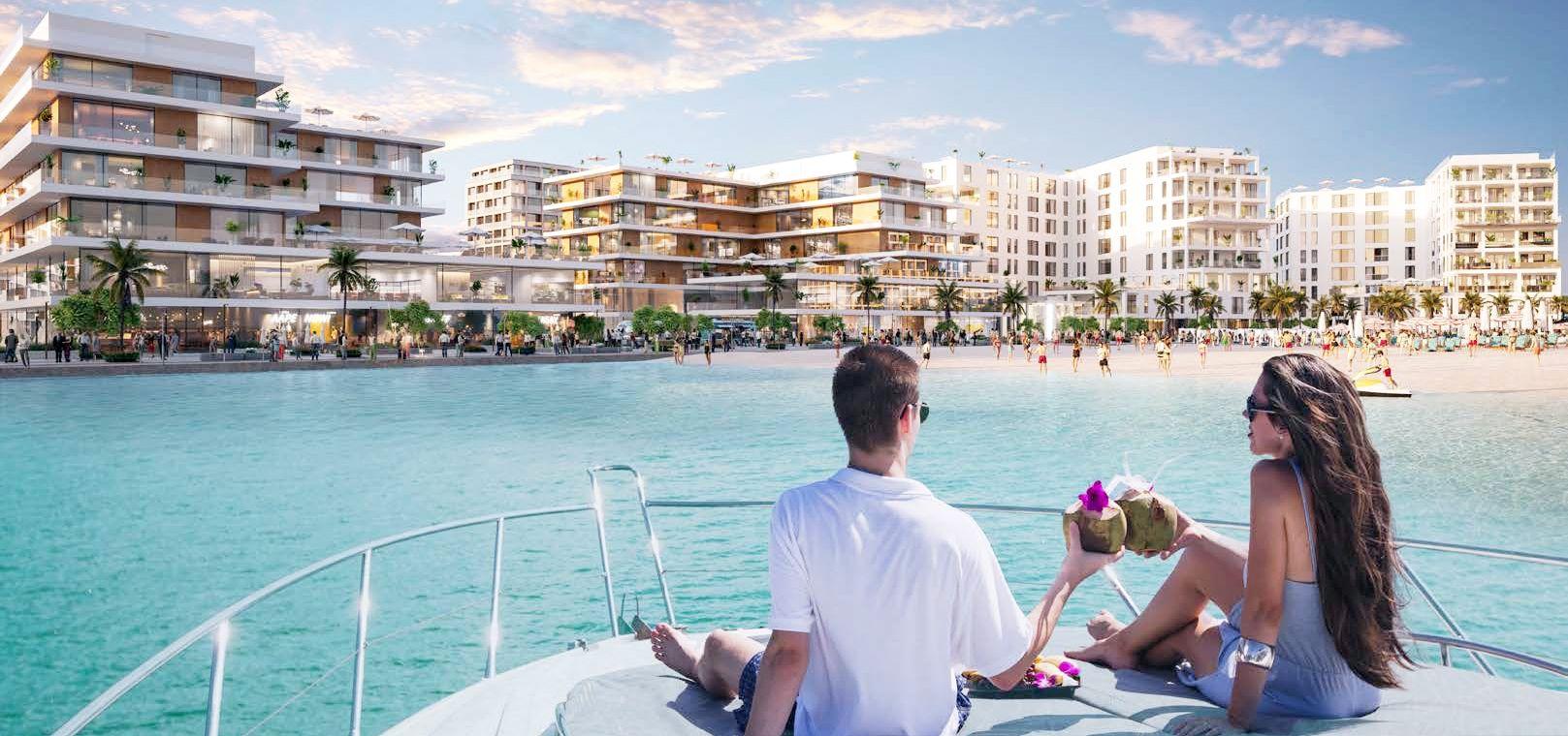 A waterfront community at Yas Acres North Bay on Yas Island, featuring modern low-rise structures, green landscaped paths, pedestrian-friendly promenade, and calm turquoise canal waters with distant skyline under daylight.